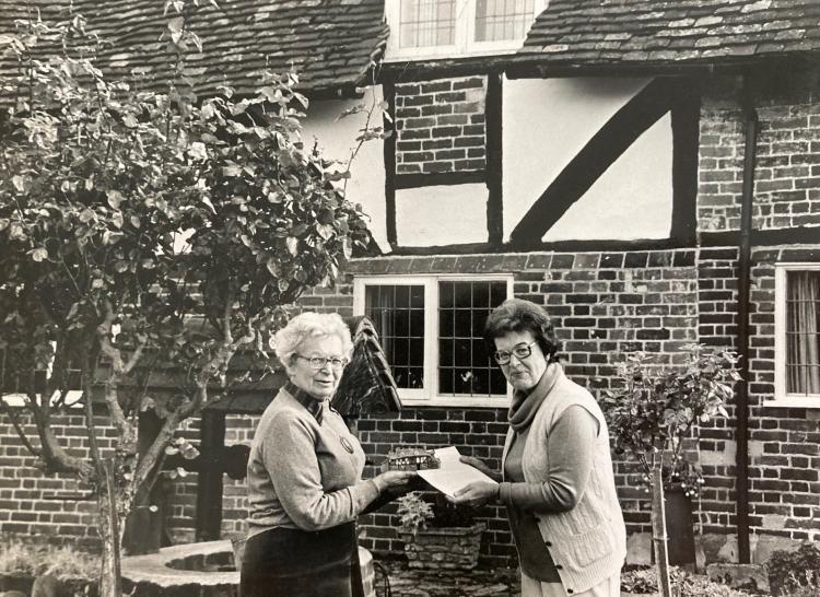 Joan Harding (left) outside Rose Tree Cottage, Binscombe handing over a report and model of the cottage.